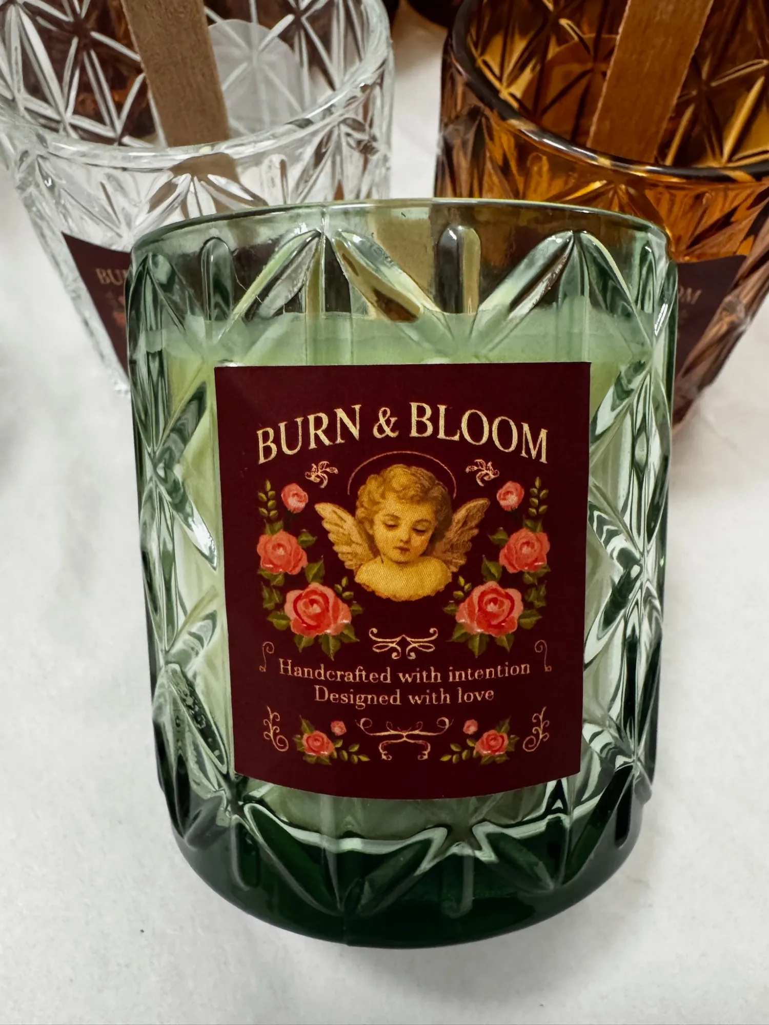 A candle in a green cut-glass jar with a Burn & Bloom label